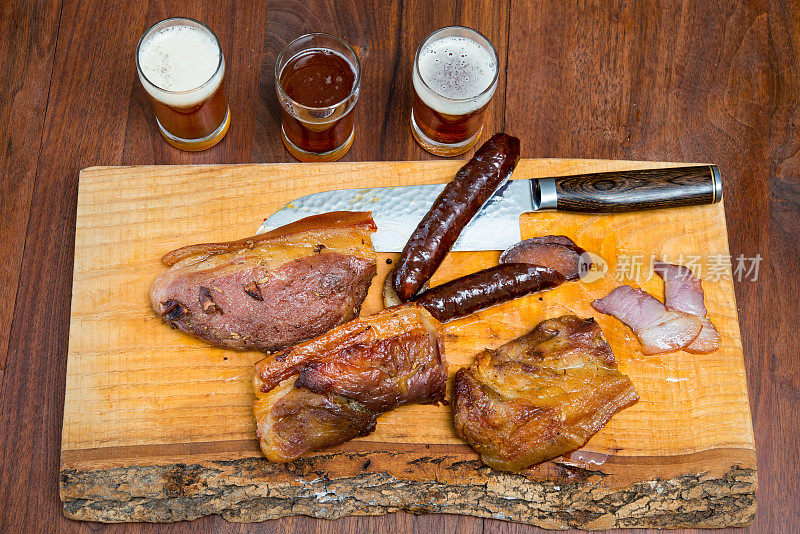 熏猪肉和香肠放在切菜板上，旁边放啤酒
