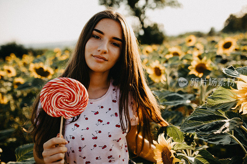 一个年轻女子在向日葵地里拿着糖果