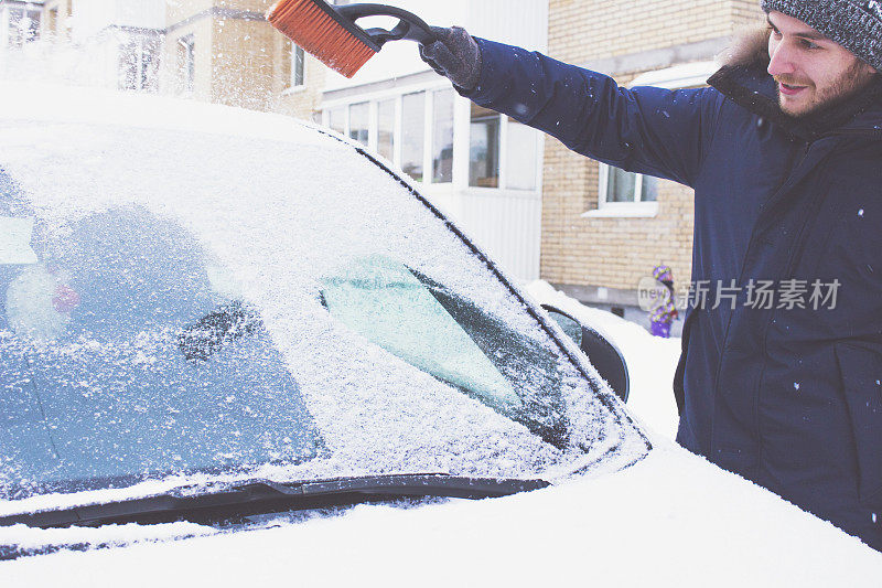 一个男人把车从雪里清理出来