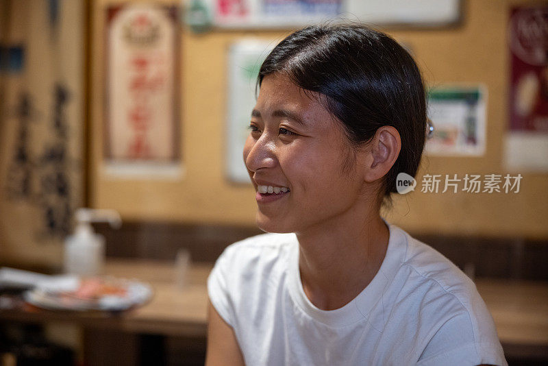 年轻女子在日本的居酒屋酒吧听朋友说话