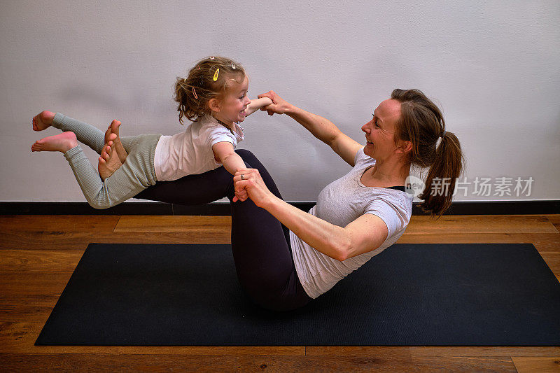 妈妈和婴儿瑜伽-肖像的母亲和女儿练习瑜伽一起在瑜伽垫上