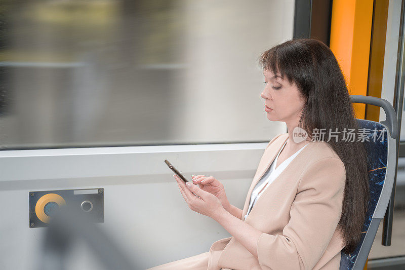 女性在公共交通工具上使用智能手机。公车上拿手机的女孩。