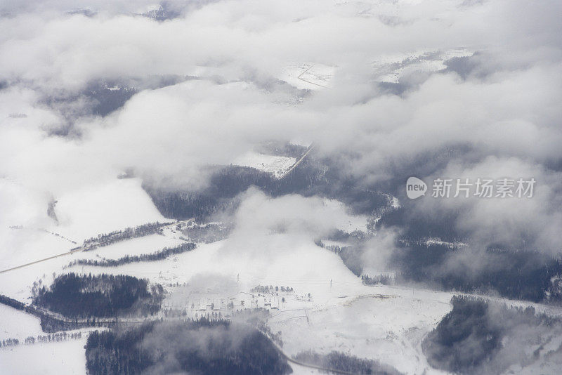 从飞机窗口透过白云看到的冬季地球景观。