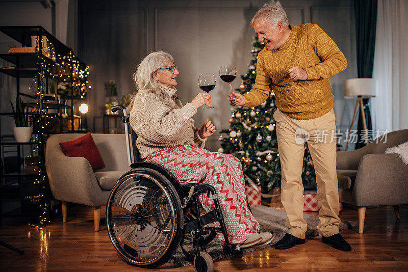 老夫妇在家里的圣诞树旁喝酒