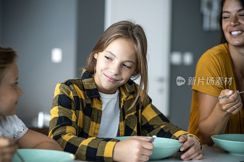 十几岁的女孩和小妹妹在厨房吃饭