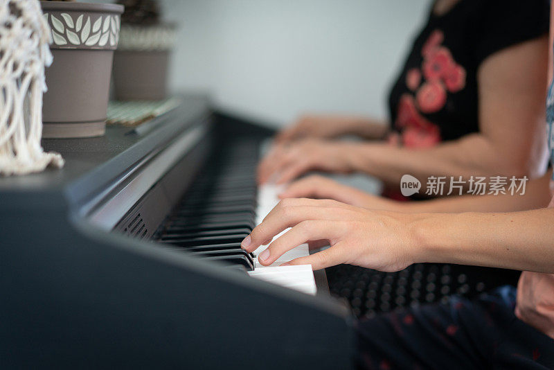 特写老年妇女教一个小男孩用乐谱弹钢琴。