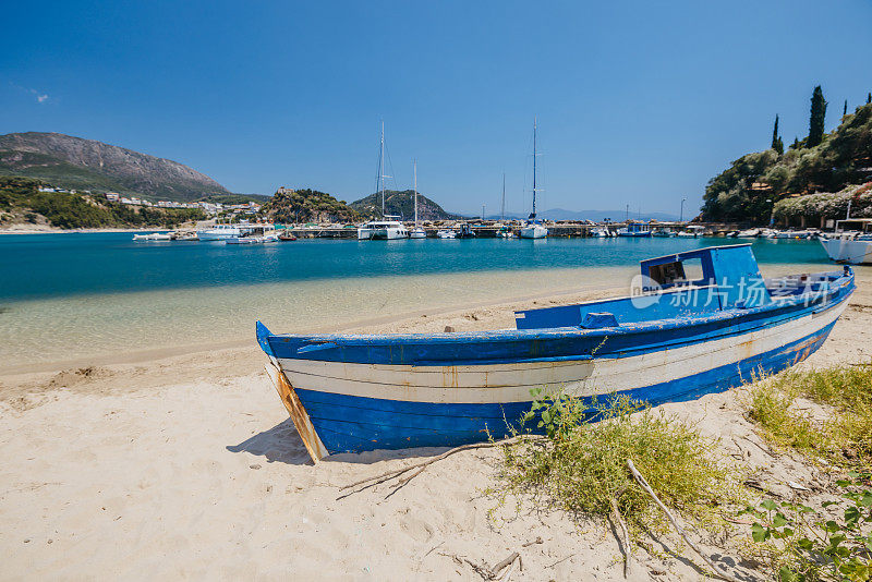 湛蓝的老船停泊在海港的沙滩上，迎着晴朗的天空