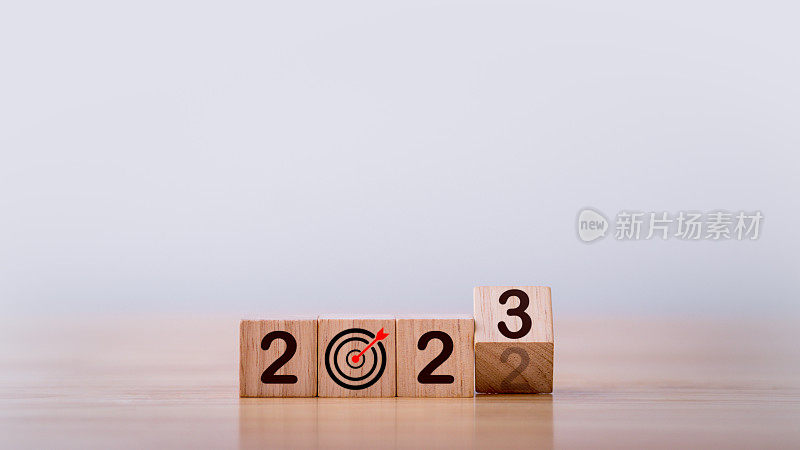 2023目标，目标，新年快乐，庆祝，背景，行动，计划，想法，和灵感概念。翻转木块将2022年变成2023年，并附上目标和目标符号。目标2023的概念