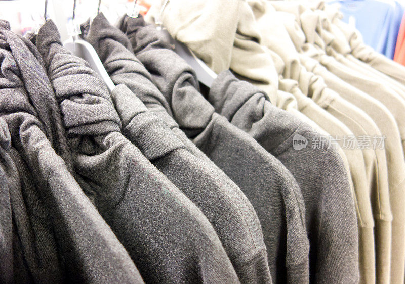 一家服装店的衣架上挂着灰色和乳白色的卷领毛衣