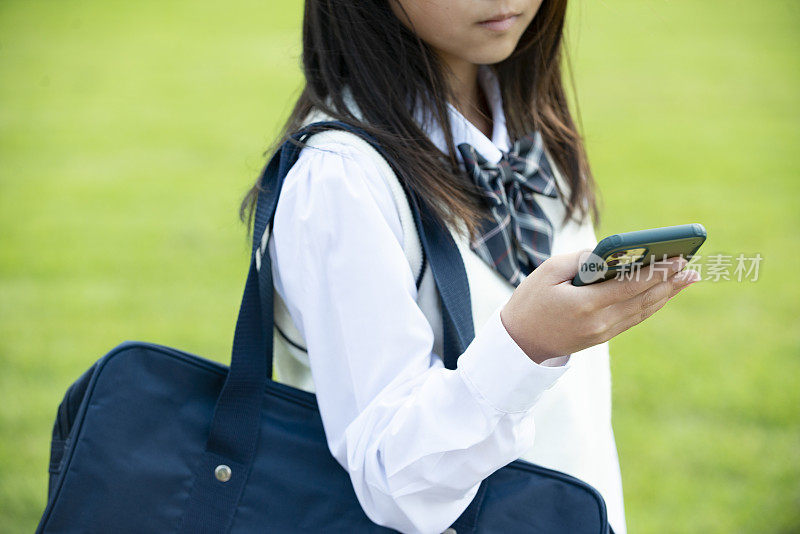穿着校服的女学生拿着智能手机