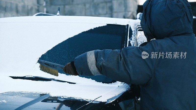 降雪后，一名妇女正在清洗家用汽车