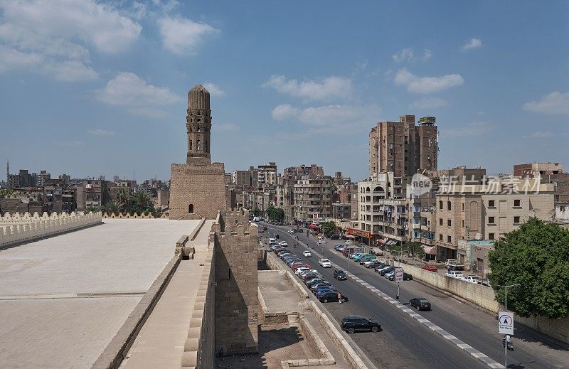 埃及开罗的哈基姆清真寺，阳光明媚的日子里，汽车在路上行驶