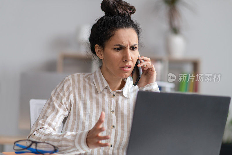 困惑的年轻女商人用笔记本电脑打电话，电脑有问题，在办公室工作