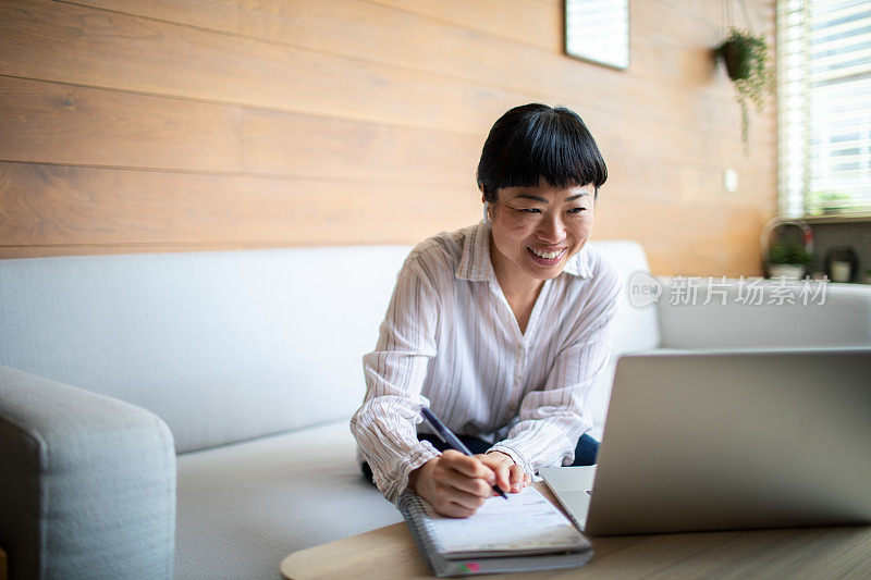 年轻的亚洲女性在家用笔记本电脑工作