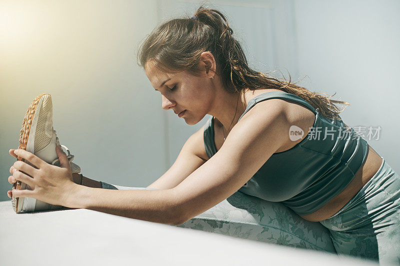 专注女性伸展脚健身训练，户外表现和坚定的承诺。冷静的女运动员热身腿部运动锻炼，肌肉活动和灵活的锻炼跑步