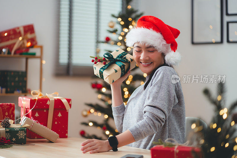 亚洲女子兴奋地摇着圣诞礼盒好奇地说。