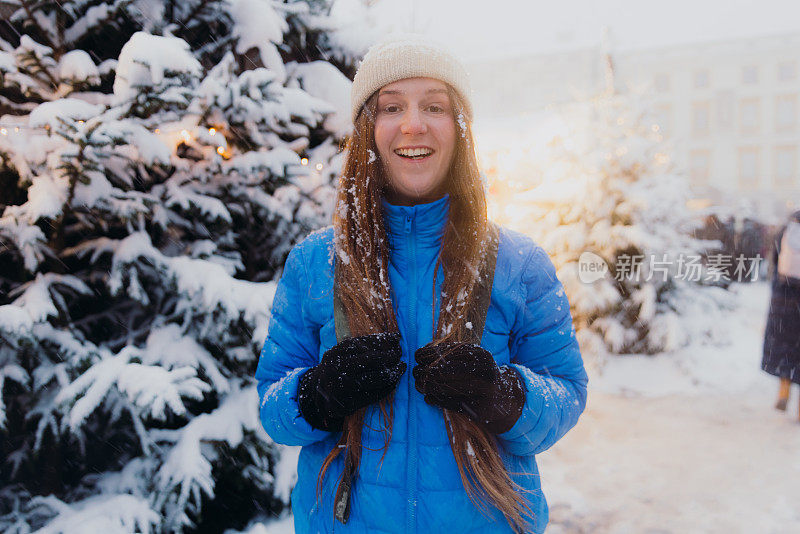 快乐的女人背着背包，在克拉科夫思考下雪的圣诞节