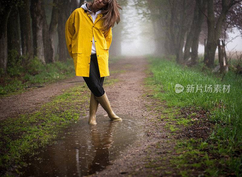 穿雨衣的女人俯视着水坑