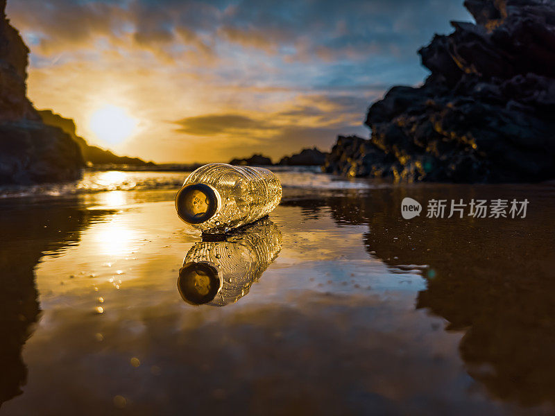 葡萄牙，日落时分，一个装满垃圾的空塑料瓶被遗忘在沙滩上