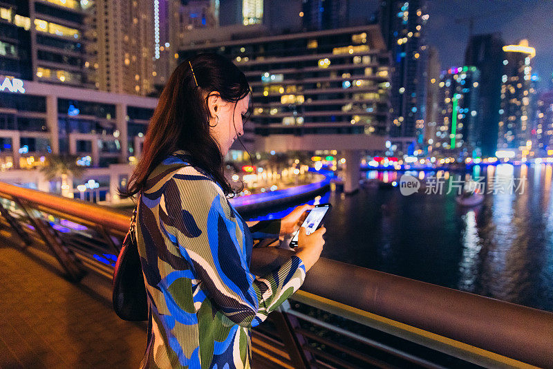 迪拜码头夜间使用智能手机的女企业家