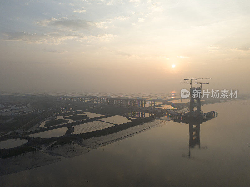 日出时正在建造的跨海大桥的航拍照片