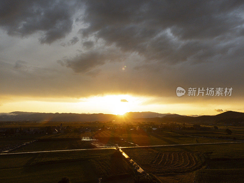 雷雨过后，落日笼罩在云和阳光下的乡村风景上