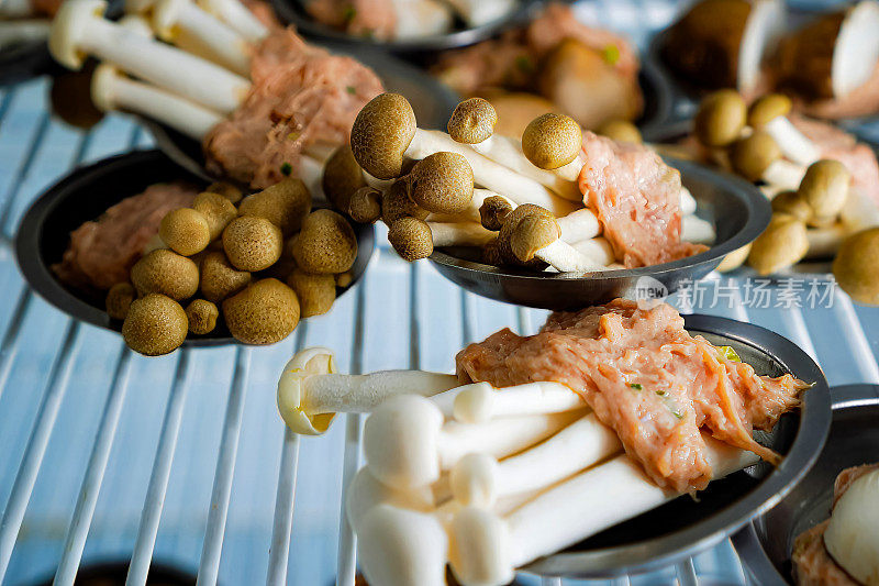 泰国的点心，餐桌上的竹制蒸笼里，猪肉裹在蘑菇里