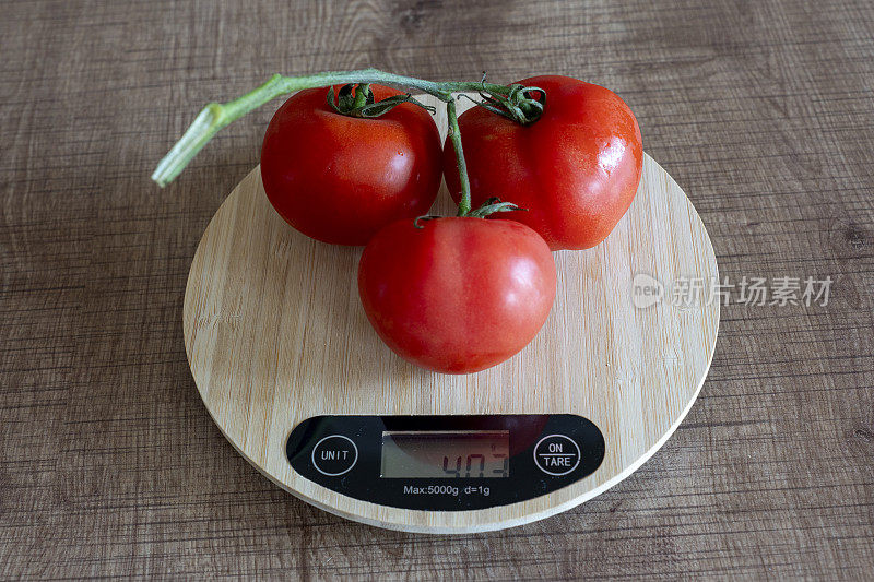 用厨房秤称西红柿的重量。