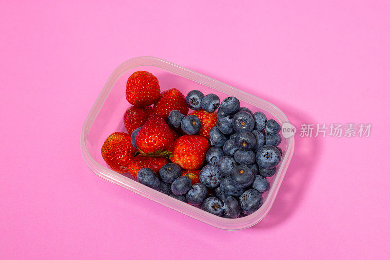 背景是蓝莓和草莓装在回收塑料盒里。