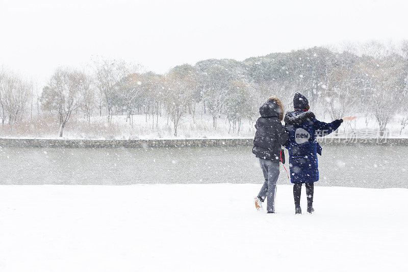 女性朋友穿着暖和的衣服在雪地里欢呼