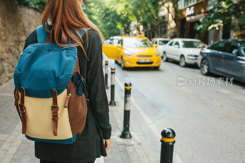 一个背着背包的年轻女游客在大城市里等出租车。的旅程。观光。旅行。