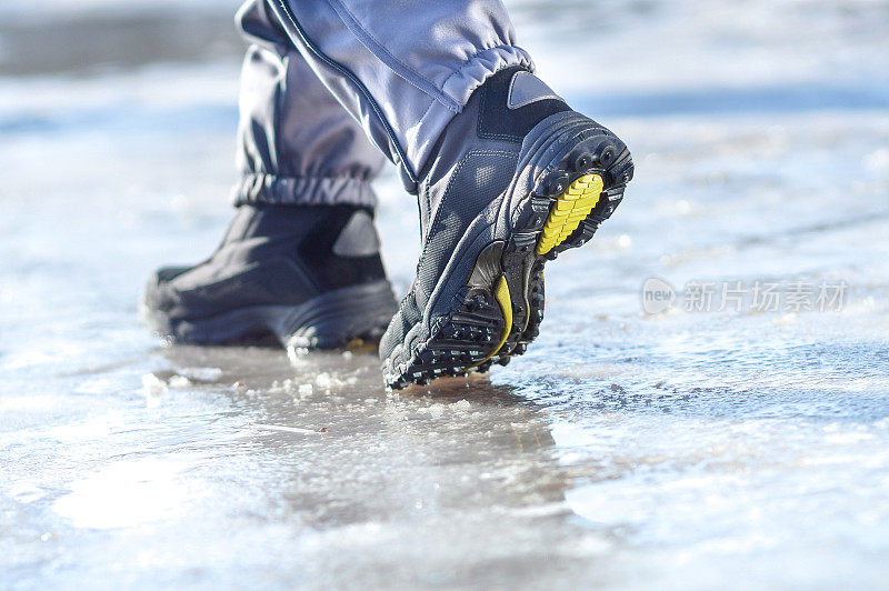 冬天的腿穿着靴子走在冰雪覆盖的路上
