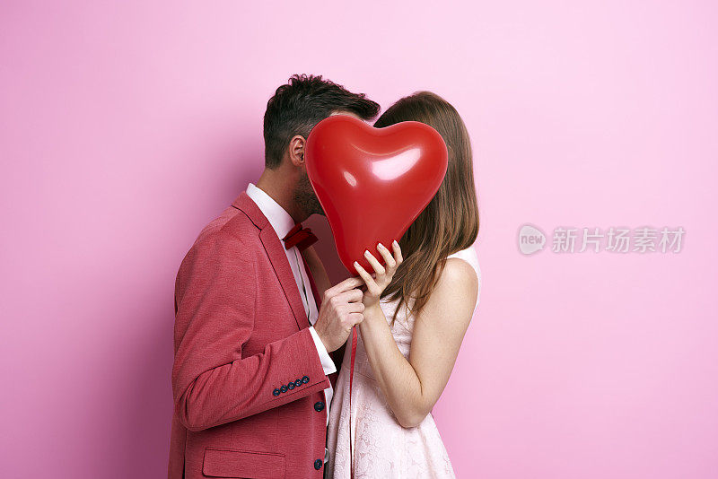 深情的夫妇用气球覆盖脸和亲吻