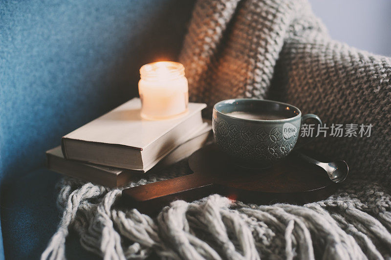 在家度过一个舒适的冬季周末。早上喝咖啡或可可，看书，暖和的针织毯子和北欧风格的椅子。Hygge概念。