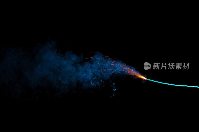 燃烧的引信与火花和蓝色烟雾隔离在黑色背景