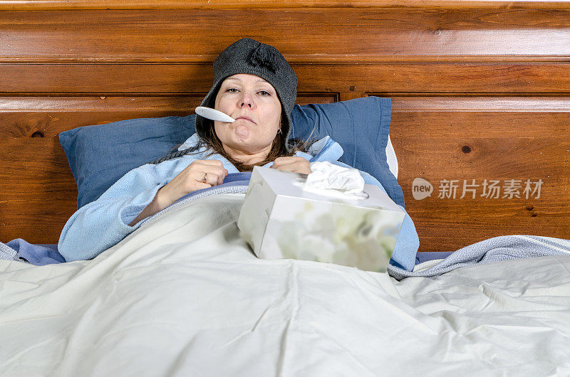 有个女人卧病在床，嘴里叼着温度计，还有一盒纸巾