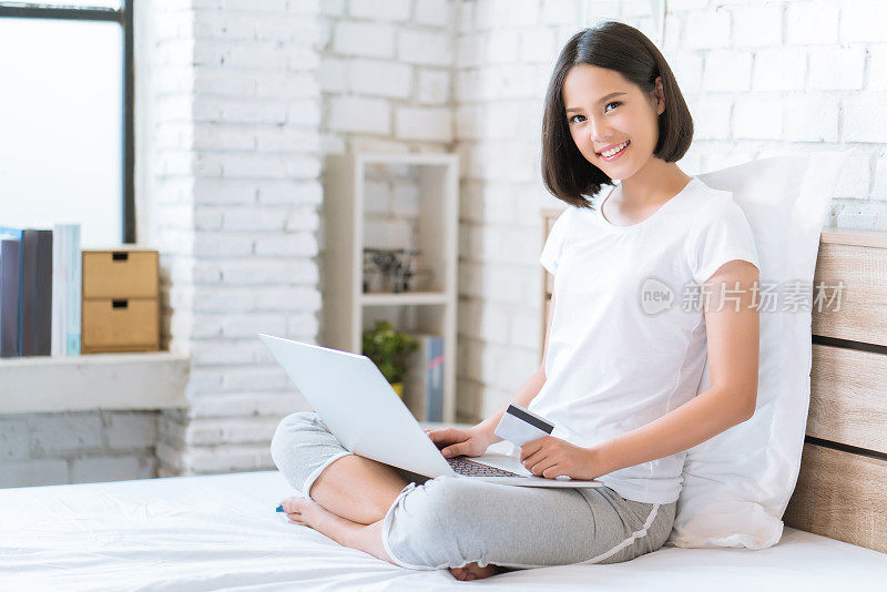 亚洲女人在床上用信用卡在网上购物