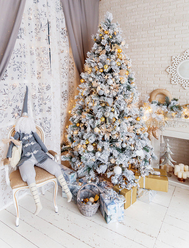 圣诞树和除夕夜。冬天假日的背景。内部细节-镜子雪花，壁炉与灯泡花环，许多礼物和小精灵的礼物。