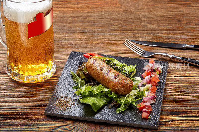 烤香肠和啤酒放在木桌上。俯视图