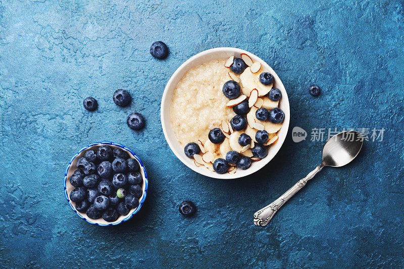 一碗香蕉和蓝莓燕麦粥，放在复古桌面上，平铺风格。自制的早餐。