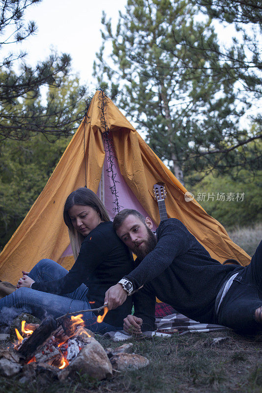 幸福的夫妇在森林里的篝火上烤香肠