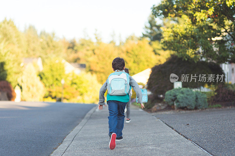 一个小弟弟和一个小妹妹一起穿过郊区去上学