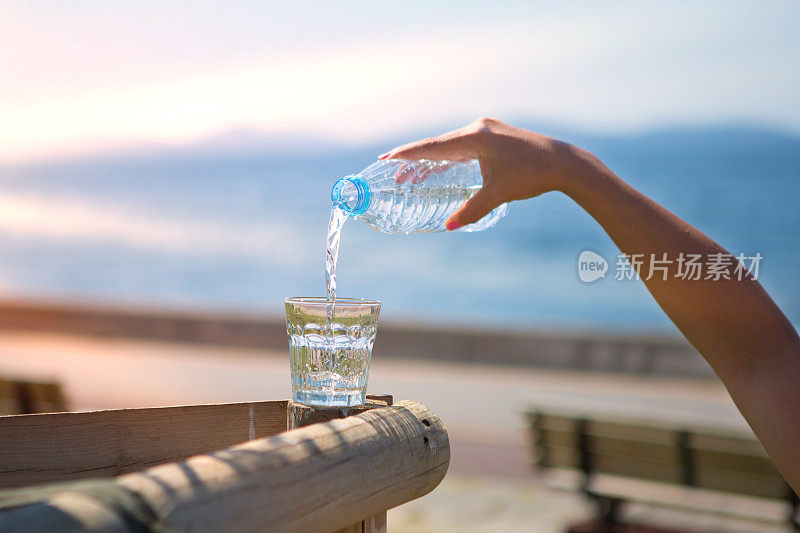 那只手正在把瓶子里的水倒在海滩上。