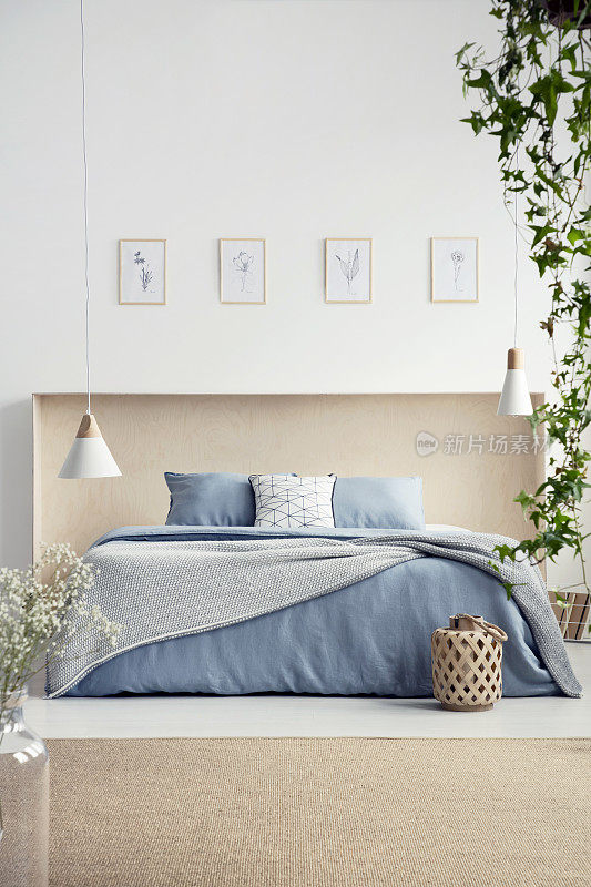 卧室内配有海报和地毯的蓝色床上配有床单和枕头的灯。真实的照片