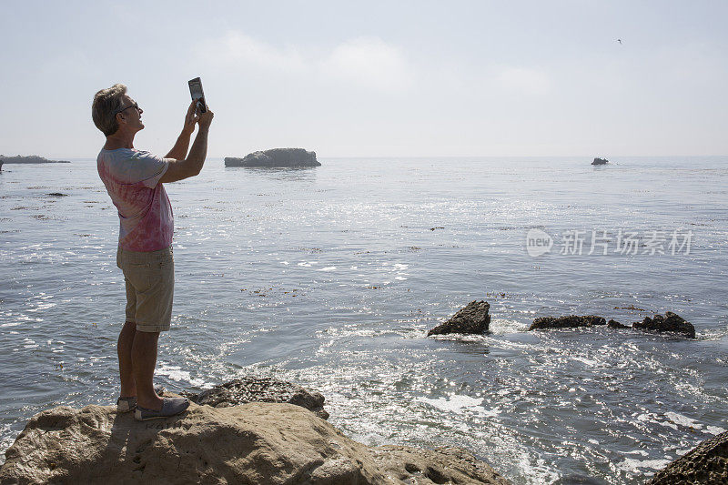 男子在海上用数码平板电脑拍照