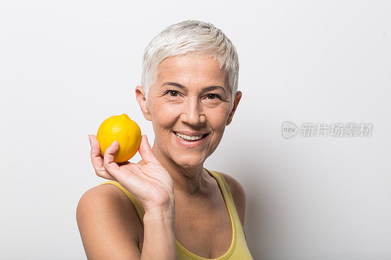 微笑着的成熟女人拿着一个柠檬