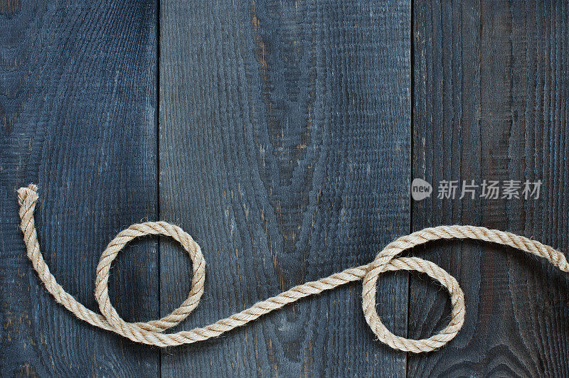 扭曲的绳子在旧的木制背景上