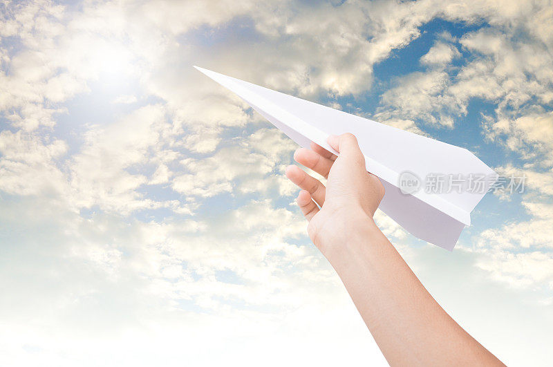 手握纸飞机向着阴云密布的蓝天飞去。