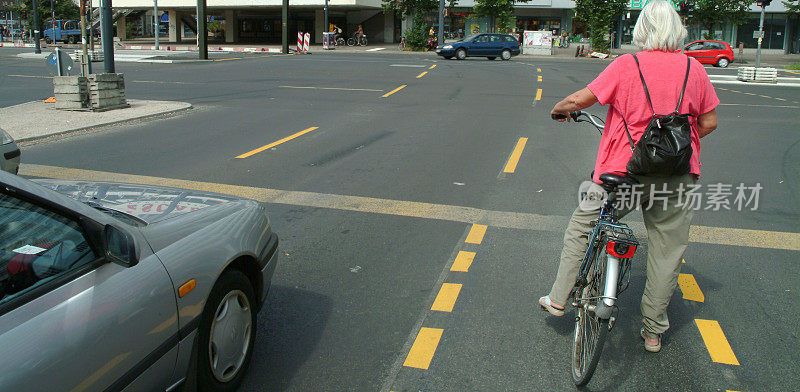 骑自行车的老妇人在十字路口等着