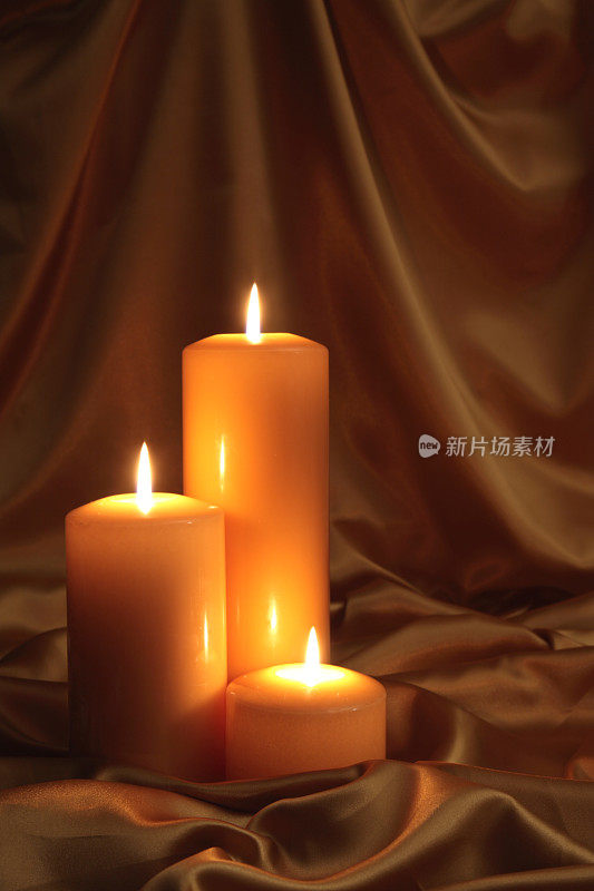 三支燃烧的蜡烛在缎子上发出金色的光芒